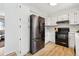 White kitchen with stainless steel refrigerator and black oven and hardwood floors at 28254 Tresine Dr, Evergreen, CO 80439