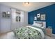 Stylish bedroom featuring a leafy comforter, natural light, and a blue accent wall at 5210 Roadrunner Ave, Firestone, CO 80504