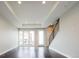 Light-filled living room with large windows, hardwood floors, tray ceiling, and adjacent staircase at 2858 W Parkside Pl, Denver, CO 80221