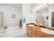 Well-lit bathroom with double vanity, tub, and shower featuring modern fixtures at 13706 Legend Trail # 104, Broomfield, CO 80023