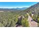 Picturesque aerial view of a mountain home surrounded by a lush green forest and distant mountain views at 31324 Kings Vly, Conifer, CO 80433