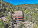Stunning aerial view of a cozy mountain home nestled among lush trees on a rocky cliff at 31324 Kings Vly, Conifer, CO 80433