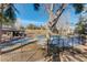 View of a tennis court and clubhouse beyond a fence, nestled among trees and a sunny sky at 23634 Pondview Pl # B, Golden, CO 80401