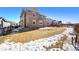 Spacious backyard featuring a grass lawn, partial snow cover, and patio area at 9335 Dunraven Loop, Arvada, CO 80007