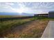 Spacious backyard with meadow grasses, fencing, and metal outbuilding on a property that backs to open space at 11595 Pass Me By Rd, Strasburg, CO 80136