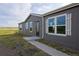 Side view of a gray home with white trim, featuring shutters, a glass front door, and a well-kept yard at 11595 Pass Me By Rd, Strasburg, CO 80136