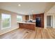 Well-lit kitchen with wood cabinets, breakfast bar, stainless steel appliances, and wood laminate flooring at 11595 Pass Me By Rd, Strasburg, CO 80136