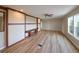 Bright living room with wood flooring, built-in bench, ceiling fan, and large windows for natural light at 11595 Pass Me By Rd, Strasburg, CO 80136