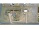 Aerial view of a large rectangular lot with a main home, large shop, mature trees, and fencing on a partially cloudy day at 2840 Wagner St, Strasburg, CO 80136