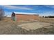 A metal barn with garage doors and a concrete pad in a field on a sunny day at 2840 Wagner St, Strasburg, CO 80136