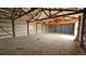 Barn interior with metal walls, concrete floor, exposed beams, and a garage door in the background at 2840 Wagner St, Strasburg, CO 80136