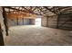 A barn interior with metal walls, a cracked concrete floor, and an open doorway at 2840 Wagner St, Strasburg, CO 80136