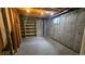 Unfinished basement with concrete walls, exposed ceiling, small window, and wooden shelving unit at 2840 Wagner St, Strasburg, CO 80136