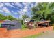 View of home featuring a modern orange fence, carport, landscaping, shed, and mature trees at 3429 Avenue D, Kittredge, CO 80457