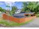House with a shed, carport, modern orange fence, and mature trees on a sunny day at 3429 Avenue D, Kittredge, CO 80457