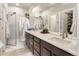 Modern bathroom featuring a dual sink vanity, large mirror and sleek glass shower with a white tile surround at 1525 W 68Th Ave, Denver, CO 80221