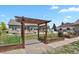 Landscaped backyard with a wooden pergola, raised garden beds, a lush lawn, and privacy fencing at 4714 Carmichael Ct, Brighton, CO 80603