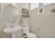 Cozy powder room offering a pedestal sink, decorative shelving, and natural lighting at 12348 W Gould Ave, Littleton, CO 80127