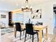 Well-lit dining room with modern chandelier, sleek wooden table, and views into the living room at 4192 S Vrain St, Denver, CO 80236
