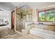 Bright bathroom with a glass enclosed shower, bathtub, tiled walls, and large window at 11072 Zephyr St, Broomfield, CO 80021