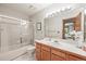Bright bathroom featuring a shower-tub combo, oak vanity, white countertops, and tiled walls at 11072 Zephyr St, Broomfield, CO 80021