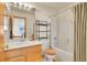 Full bathroom with shower-tub combo, vanity, and a decorative shelf unit over toilet at 1214 S Akron Way, Denver, CO 80247