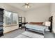 Bright bedroom with large window, ceiling fan, gray carpet, and sleek black furniture at 1214 S Akron Way, Denver, CO 80247