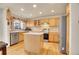 Well-lit kitchen featuring wood cabinets, stainless steel appliances, hardwood floors, and center island at 1214 S Akron Way, Denver, CO 80247