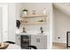 Elegant bar area with gray cabinets, wine fridge, open shelving, and modern fixtures adjacent to dining at 8280 E 36Th Ave # 27, Denver, CO 80238