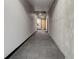 Long hallway with concrete accent wall and carpet featuring a geometric design, plus a plant near the unit door at 1020 15Th St # 210, Denver, CO 80202