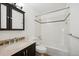 Bathroom featuring a modern vanity, a commode, and a bathtub with a white tiled surround and decorative border at 13895 W Atlantic Ave, Lakewood, CO 80228