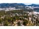 Aerial view of a snow dusted mountain neighborhood nestled among trees with the home featured prominently at 9189 Fallen Rock Rd, Conifer, CO 80433