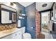 Stylish bathroom with a vibrant blue accent wall, a decorative mirror, and a shower with a floral curtain at 9189 Fallen Rock Rd, Conifer, CO 80433
