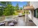 View of outdoor table and four chairs on wood deck with white railing, trees and entrance to the house at 9189 Fallen Rock Rd, Conifer, CO 80433