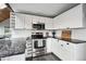 Bright kitchen with white cabinets, stainless steel appliances, and a granite countertop, complemented by a wood ceiling at 9189 Fallen Rock Rd, Conifer, CO 80433