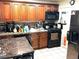Well-lit kitchen featuring warm wood cabinetry, black appliances, and a tile backsplash, and stone dining table at 4411 W Center Ave, Denver, CO 80219