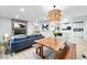 Open-concept dining area with a rustic wooden table, seamlessly connecting to the living room and kitchen at 3067 Robin Way, Denver, CO 80222