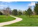 Scenic view of a winding walking path through a lush green park with mature trees at 12535 Forest View St, Broomfield, CO 80020