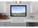 Modern kitchen with white cabinets, stainless steel appliances, and a farmhouse sink with a view at 7575 E Windlawn Way, Parker, CO 80134