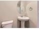 The bathroom features a pedestal sink, a round mirror, a toilet, and neutral-toned walls at 11771 W Quarles Ave, Littleton, CO 80127