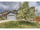 Lovely two-story home with a blooming tree in the yard, a gray garage, and stone accents at 11771 W Quarles Ave, Littleton, CO 80127