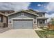 Charming two-story home with a gray siding, stone accents, and a large two car garage at 11771 W Quarles Ave, Littleton, CO 80127