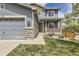Inviting two-story home featuring a covered porch with stone pillars and a well-manicured lawn at 11771 W Quarles Ave, Littleton, CO 80127