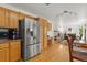 Open kitchen layout with stainless steel refrigerator, wooden cabinets, and a view into the living room at 408 Sylvestor Trl, Highlands Ranch, CO 80129