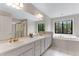 Bright bathroom with dual sinks, vanity, and a separate tub with large window at 1311 Fletcher Dr, Erie, CO 80516