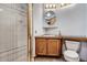 Neutral toned bathroom featuring a shower with sliding doors and a wood vanity with a framed round mirror at 14076 E Radcliff Cir, Aurora, CO 80015