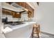 This kitchen features stainless steel appliances, a breakfast bar with stone countertops, and wooden stools at 14076 E Radcliff Cir, Aurora, CO 80015