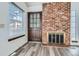 Warm and bright living room featuring a brick fireplace and wood-look flooring at 14076 E Radcliff Cir, Aurora, CO 80015