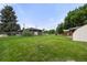 Large, fenced backyard with lush green grass and mature trees at 8198 E Lehigh Dr, Denver, CO 80237