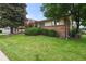 Well-kept front yard of a single Gathering home, featuring mature landscaping and an American flag at 8198 E Lehigh Dr, Denver, CO 80237